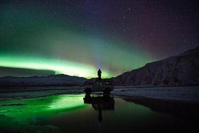 一名男子站在SUV上观看北极光